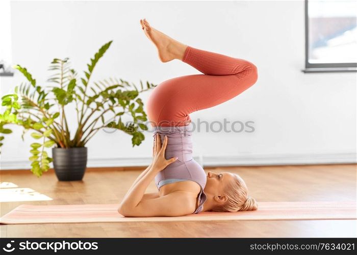 fitness, people and healthy lifestyle concept - young woman doing yoga in supported shoulderstand at home. woman doing yoga in shoulderstand at home