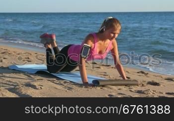 Fitness routine for women - athletic girl doing push-ups on beach