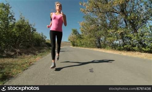 Fitness routine for women - athletic girl runner jogging along road wide angle