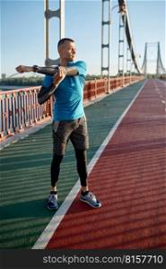 Fitness runner doing warm-up routine before speed running. Man stretching arms muscles preparing for cardio workout fast jogging. Fitness runner doing warm-up routine before speed running