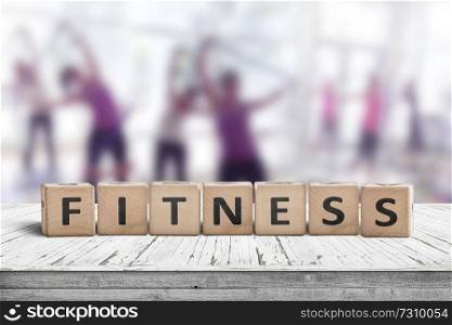 Fitness sign on a table in a gym with women training in the background