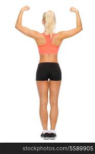 fitness, sport and diet concept - sporty woman form the back flexing her biceps