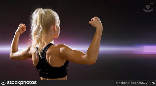 fitness, sport and diet concept - sporty woman form the back flexing her biceps