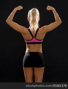 fitness, sport and diet concept - sporty woman from the back flexing her biceps