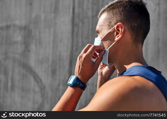fitness, sport and health concept - young man in medical mask doing sports outdoors. young man in medical mask doing sports outdoors