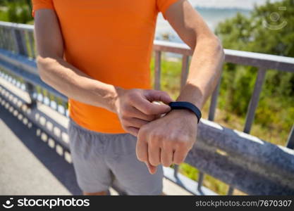fitness, sport and healthy lifestyle concept - close up of young man with fitness tracker at seaside. close up of man with fitness tracker outdoors