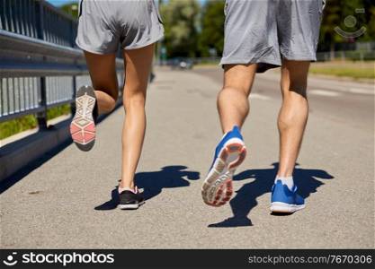 fitness, sport and healthy lifestyle concept - feet of sporty couple running along city road. feet of sporty couple running along city road