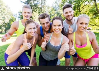 fitness, sport and healthy lifestyle concept - group of happy friends showing thumbs up at summer park. group of happy sporty friends showing thumbs up