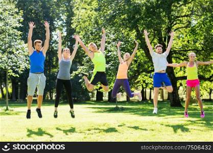fitness, sport and healthy lifestyle concept - group of happy people jumping high at park in summer. group of happy friends jumping high at park