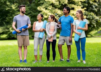 fitness, sport and healthy lifestyle concept - group of happy people with yoga mats at park. group of happy people with yoga mats at park