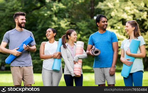 fitness, sport and healthy lifestyle concept - group of happy people with yoga mats at park. group of happy people with yoga mats at park