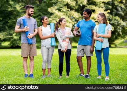 fitness, sport and healthy lifestyle concept - group of happy people with yoga mats at park. group of happy people with yoga mats at park