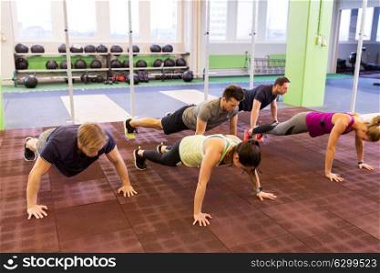 fitness, sport and healthy lifestyle concept - group of people doing push-ups in gym. group of people doing push-ups in gym