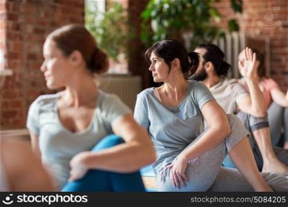 fitness, sport and healthy lifestyle concept - group of people doing yoga seated spinal twist pose in gym or studio. group of people doing yoga exercises at studio. group of people doing yoga exercises at studio