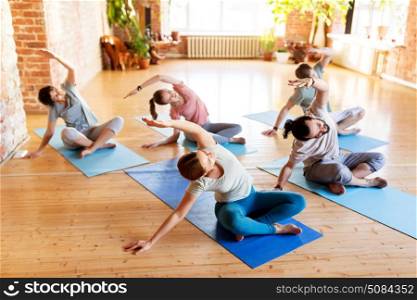 fitness, sport and healthy lifestyle concept - group of people doing yoga exercises on mats in gym or studio. group of people doing yoga exercises at studio. group of people doing yoga exercises at studio