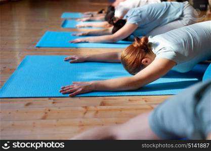 fitness, sport and healthy lifestyle concept - group of people doing yoga hare pose on mats at studio. group of people doing yoga hare pose at studio