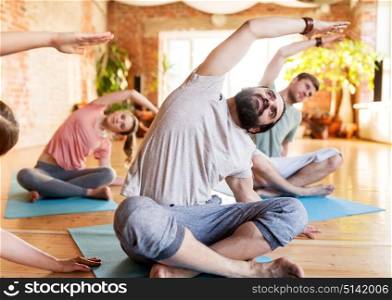 fitness, sport and healthy lifestyle concept - group of people doing yoga exercises on mats in gym or studio. group of people doing yoga exercises at studio