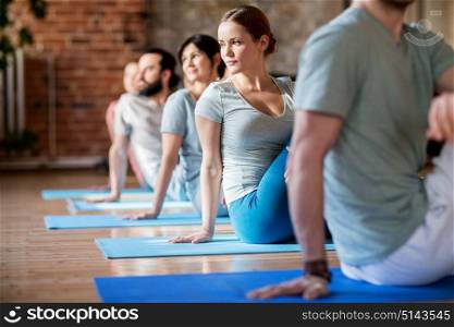 fitness, sport and healthy lifestyle concept - group of people doing yoga seated spinal twist pose in gym or studio. group of people doing yoga exercises at studio