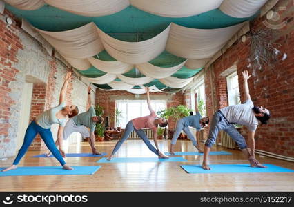 fitness, sport and healthy lifestyle concept - group of people doing yoga in triangle pose at studio. group of people doing yoga triangle pose at studio