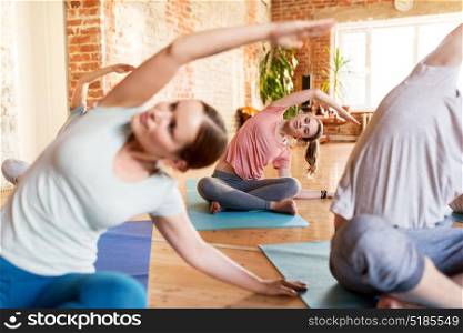 fitness, sport and healthy lifestyle concept - group of people doing yoga exercises on mats in gym or studio. group of people doing yoga exercises at studio