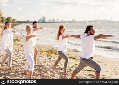 fitness, sport and healthy lifestyle concept - group of people making yoga in warrior pose on beach