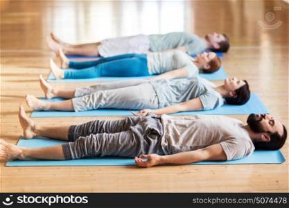 fitness, sport and healthy lifestyle concept - group of people making yoga exercises on mats at studio. group of people making yoga exercises at studio