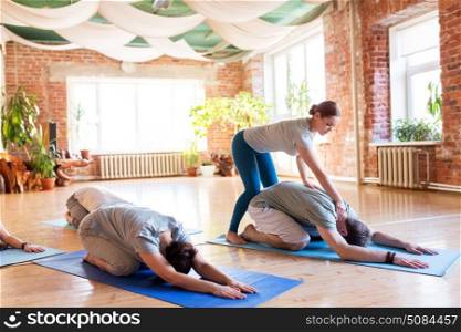 fitness, sport and healthy lifestyle concept - group of people with personal trainer doing yoga exercises on mats in gym or studio. group of people doing yoga exercises at studio. group of people doing yoga exercises at studio
