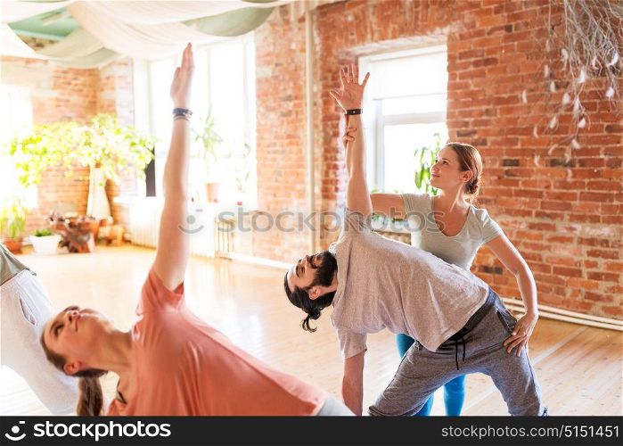 fitness, sport and healthy lifestyle concept - group of people with personal trainer doing yoga exercises on mats in gym or studio. group of people doing yoga exercises at studio