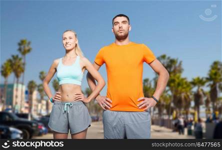 fitness, sport and healthy lifestyle concept - happy couple exercising at summer over venice beach background in california. couple doing sports at summer over venice beach. couple doing sports at summer over venice beach