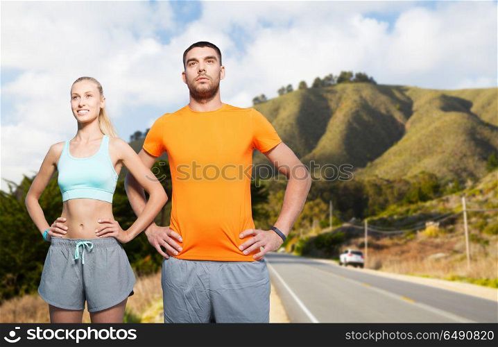 fitness, sport and healthy lifestyle concept - happy couple exercising over big sur hills and road background in california. happy couple doing sports over big sur hills. happy couple doing sports over big sur hills