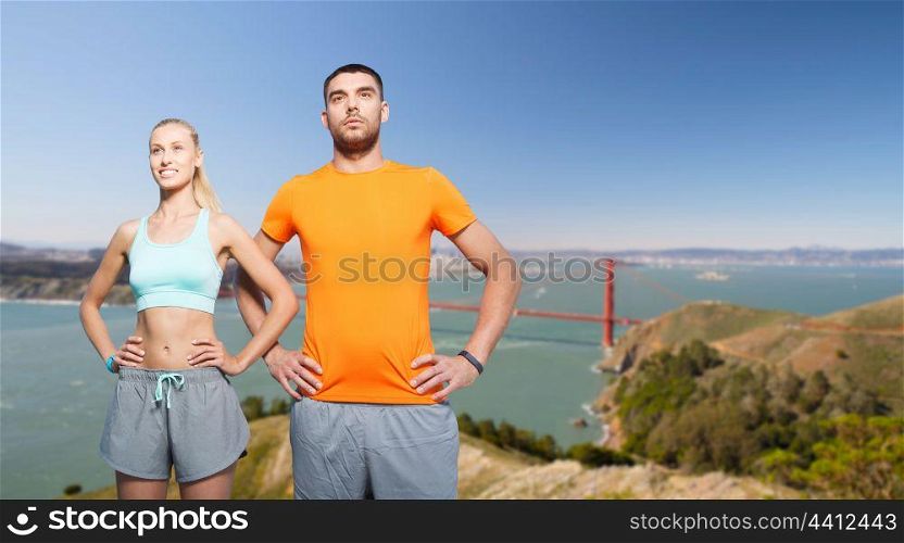 fitness, sport and healthy lifestyle concept - happy couple exercising over golden gate bridge in san francisco bay background. happy couple doing sports over golden gate bridge. happy couple doing sports over golden gate bridge