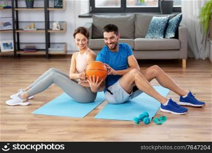 fitness, sport and healthy lifestyle concept - happy couple exercising with ball at home. happy couple exercising with ball at home