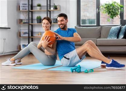 fitness, sport and healthy lifestyle concept - happy couple exercising with ball at home. happy couple exercising with ball at home