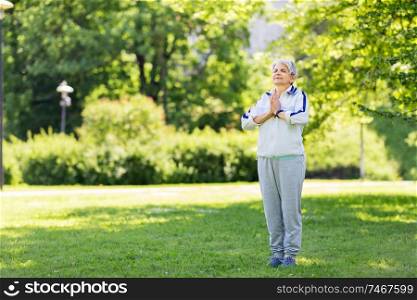 fitness, sport and healthy lifestyle concept - happy smiling senior woman doing yoga at summer park. happy senior woman doing yoga at summer park