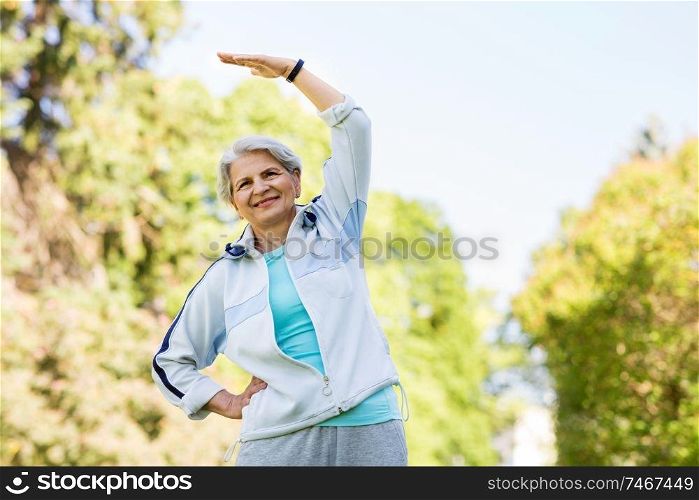 fitness, sport and healthy lifestyle concept - happy smiling senior woman exercising at summer park. happy senior woman exercising at summer park