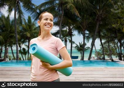fitness, sport and healthy lifestyle concept - happy smiling woman with exercise mat over swimming pool on tropical beach background in french polynesia. smiling woman with exercise mat on tropical beach