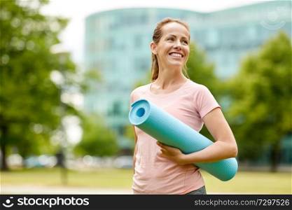 fitness, sport and healthy lifestyle concept - happy smiling woman with exercise mat at city park. happy smiling woman with exercise mat at city park