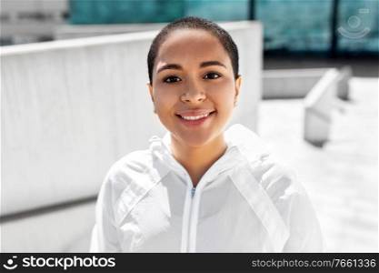 fitness, sport and healthy lifestyle concept - happy smiling young african american woman in sports clothes outdoors. african american woman in sports clothes outdoors