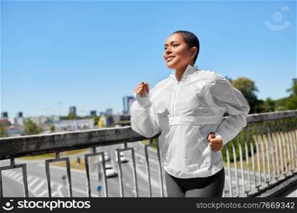 fitness, sport and healthy lifestyle concept - happy smiling young african american woman running outdoors along bridge. african american woman running along bridge