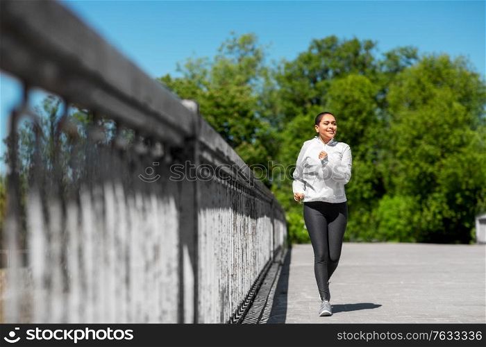 fitness, sport and healthy lifestyle concept - happy smiling young african american woman running outdoors. african american woman running outdoors