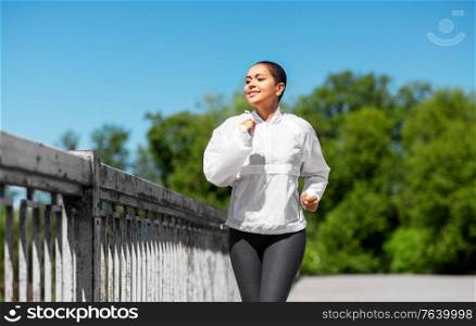 fitness, sport and healthy lifestyle concept - happy smiling young african american woman running outdoors. african american woman running outdoors