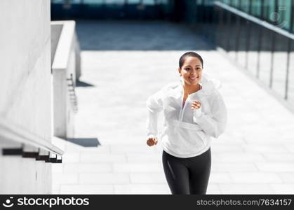 fitness, sport and healthy lifestyle concept - happy smiling young african american woman running upstairs outdoors. african american woman running upstairs outdoors