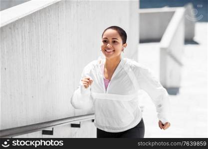 fitness, sport and healthy lifestyle concept - happy smiling young african american woman running upstairs outdoors. african american woman running upstairs outdoors