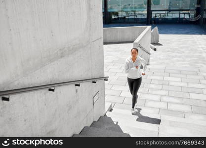 fitness, sport and healthy lifestyle concept - happy smiling young african american woman running upstairs outdoors. african american woman running upstairs outdoors