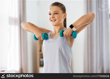 fitness, sport and healthy lifestyle concept - happy teenage girl with dumbbells exercising at home. teenage girl with dumbbells exercising at home