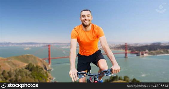 fitness, sport and healthy lifestyle concept - happy young man riding bicycle over golden gate bridge in san francisco bay background. happy man riding bicycle over golden gate bridge. happy man riding bicycle over golden gate bridge