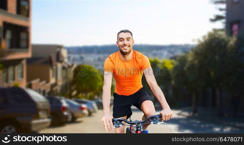 fitness, sport and healthy lifestyle concept - happy young man riding bicycle over san francisco city background. happy man riding bicycle over san francisco city. happy man riding bicycle over san francisco city