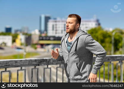 fitness, sport and healthy lifestyle concept - happy young man running across city bridge. happy young man running across city bridge