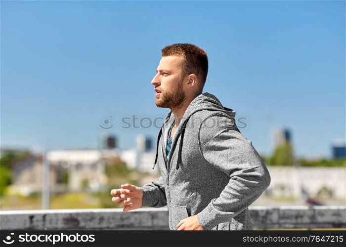 fitness, sport and healthy lifestyle concept - happy young man running across city bridge. happy young man running across city bridge