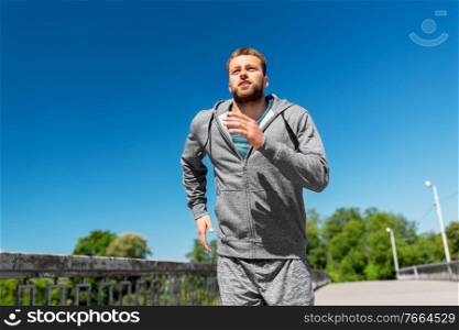 fitness, sport and healthy lifestyle concept - happy young man running across city bridge. happy young man running across city bridge